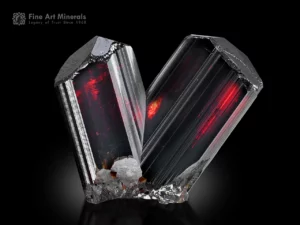V-shaped rutile crystal pair with striated prisms and multi-faced terminations, glowing fiery red under backlight, from Zagi Mountain, Pakistan.
