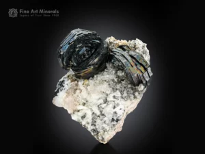 Two flower-shaped hematite clusters with iridescent sparkle on a contrasting white matrix.