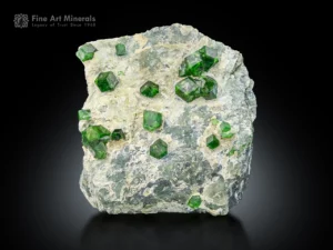 Vivid green demantoid garnet crystals on a light matrix with sharp faces and bright luster.