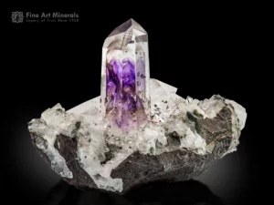 Gemmy amethyst crystal standing on quartz matrix showing deep purple to lavender color zoning and brilliant luster.