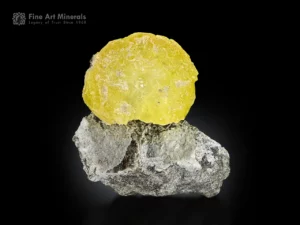 Rounded lemon yellow brucite sphere perched on grey matrix.