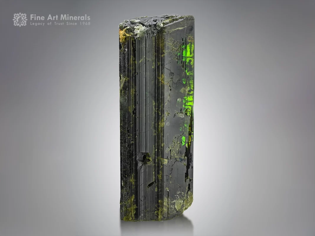 Dark epidote crystal showing bright green flashes when backlit with strong vertical striations.