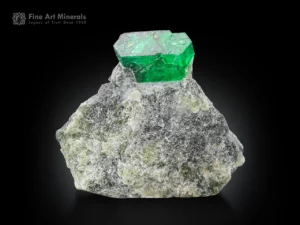 Green emerald crystal aesthetically perched on a natural rock matrix.