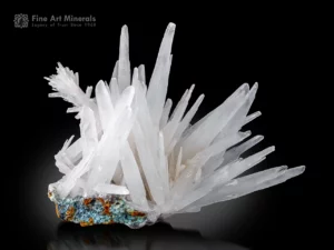 Elongated white aragonite crystals radiating over matrix with subtle chrysocolla hues