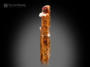 elongated bastnasite crystal with amber color and white associated crystals