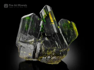 Green epidote crystal cluster with subtle honey glow and sharp striations.
