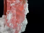 Gemmy pink fluorite crystal with glassy luster on white albite matrix.