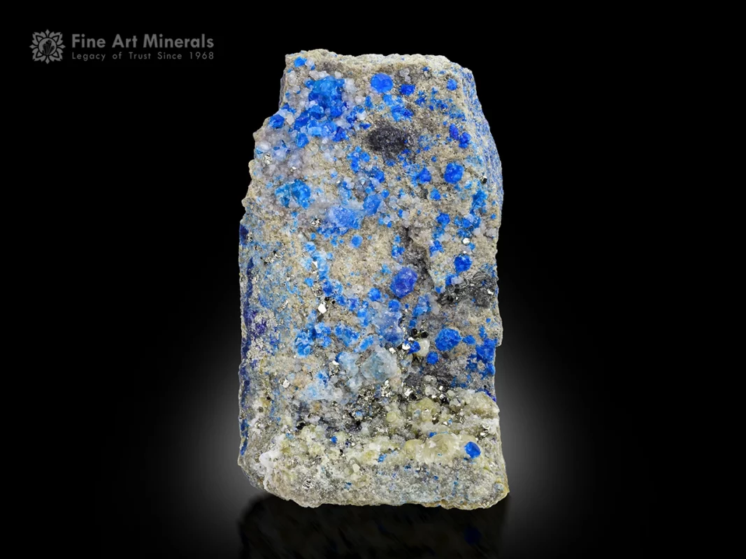 Blue hauyne crystals with pyrite on matrix showing orange fluorescence under UV light.