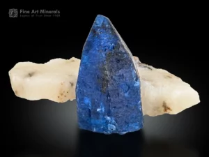 Blue Afghanite crystal on white calcite matrix showing strong contrast and orange fluorescence under UV light.