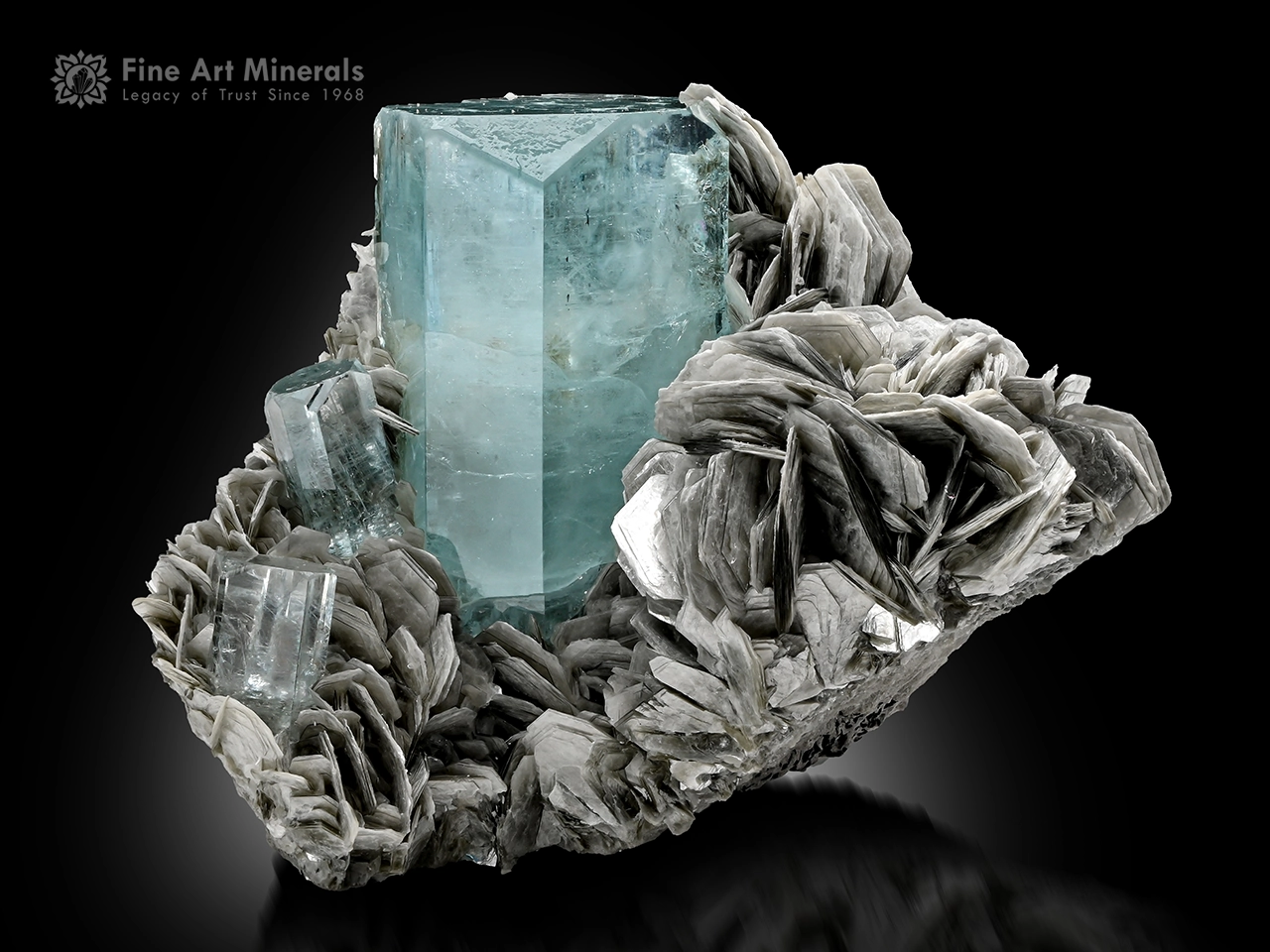 Sky-blue aquamarine crystal with two smaller crystals on a silvery muscovite matrix from Nagar Valley.