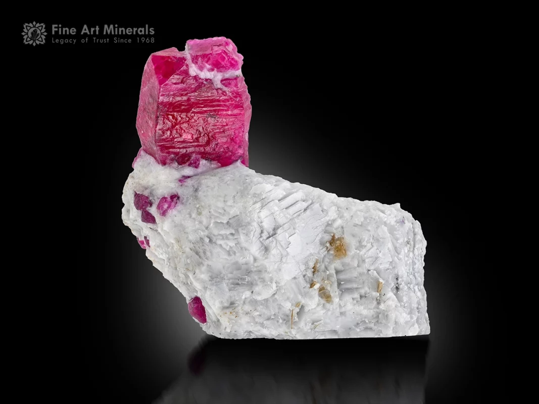 Red ruby crystal on matrix glowing under UV light with strong contrast and fine luster.