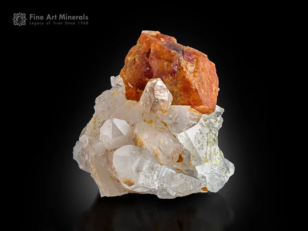 Orange scheelite crystal on a clear quartz cluster showing strong contrast and well-defined crystal form.