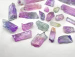Mixed lot of Kunzite crystals showing lilac and green colors with natural crystal forms and good clarity.
