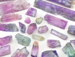 Mixed lot of Kunzite crystals showing lilac and green colors with natural crystal forms and good clarity.