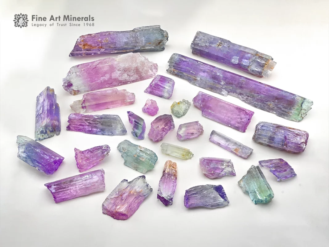 Mixed lot of Kunzite crystals showing lilac and green colors with natural crystal forms and good clarity.