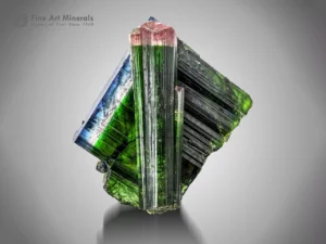 Green tourmaline crystals with pink and blue caps, displaying excellent luster and vertical striations.